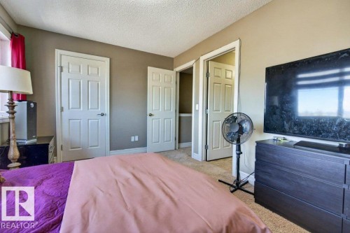 Carpeted room featuring multiple panel doors, a built-in closet with shelving, and neutral wall tones - 40 14621 121 Street, Edmonton, AB - Indoor Photo Showing Bedroom