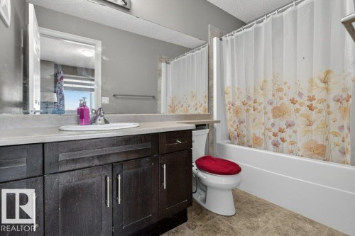 Bathroom featuring a dark wood-finish vanity with a light-toned countertop and an integrated sink - 40 14621 121 Street, Edmonton, AB - Indoor Photo Showing Bathroom