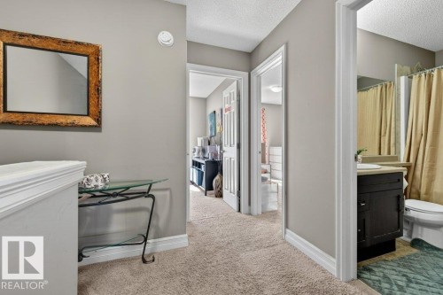 Carpeted hallway featuring warm gray wall paint, white baseboards, and a neutral ceiling - 40 14621 121 Street, Edmonton, AB - Indoor