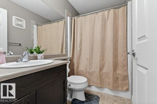 Bathroom featuring a dark wood-finish vanity with an integrated sink, a neutral countertop, and a full-width mirror - 40 14621 121 Street, Edmonton, AB - Indoor Photo Showing Bathroom