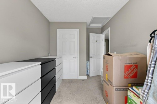 Carpeted interior space featuring light gray wall paint, white trim, and a white paneled door with a silver-tone handle - 40 14621 121 Street, Edmonton, AB - Indoor Photo Showing Other Room