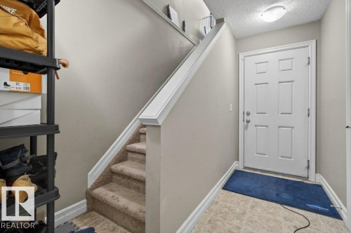 Entryway with panel-style door, contrasting baseboards, and neutral-toned tile flooring - 40 14621 121 Street, Edmonton, AB - Indoor Photo Showing Other Room