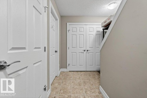 Hallway featuring tiled flooring, neutral wall color, multiple paneled doors, and a flush mount ceiling light - 40 14621 121 Street, Edmonton, AB - Indoor Photo Showing Other Room