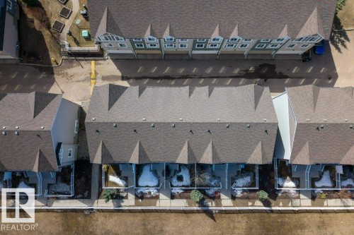 Townhouse complex featuring asphalt shingle roofing, individual fenced patios, paved common areas, and exterior siding - 40 14621 121 Street, Edmonton, AB - Outdoor