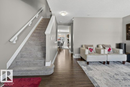 Inviting entryway featuring wood-finish flooring, a carpeted staircase with white handrails, and neutral wall tones - 40 14621 121 Street, Edmonton, AB - Indoor