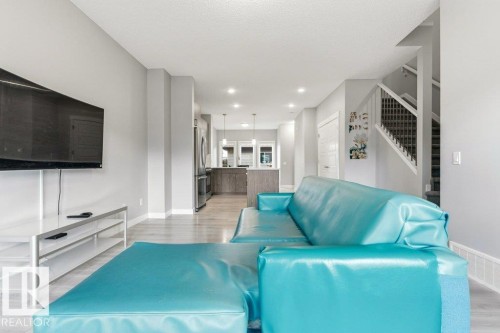 Open-concept living space featuring light gray walls, wood-finish flooring, recessed lighting, and a visible kitchen with stainless steel appliances - 17451 77 Street, Edmonton, AB - Indoor Photo Showing Other Room