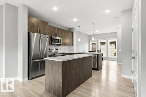 Modern kitchen featuring wood-finish cabinetry, stainless steel appliances, a white subway tile backsplash, and light wood-finish flooring - 17451 77 Street, Edmonton, AB - Indoor Photo Showing Kitchen With Upgraded Kitchen