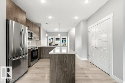 Modern kitchen featuring stainless steel appliances, wood-finish cabinetry, a subway tile backsplash, and light wood-finish flooring - 17451 77 Street, Edmonton, AB - Indoor Photo Showing Kitchen With Upgraded Kitchen