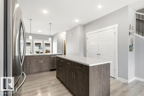 Contemporary kitchen featuring wood-finish cabinetry and a central island with a light-toned countertop - 17451 77 Street, Edmonton, AB - Indoor Photo Showing Kitchen With Upgraded Kitchen