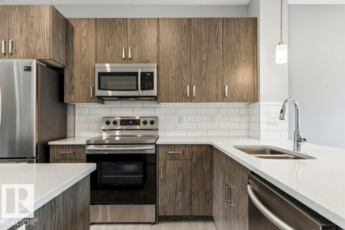 Kitchen featuring wood-finish cabinetry, stainless steel appliances, white subway tile backsplash, and light-toned countertops - 17451 77 Street, Edmonton, AB - Indoor Photo Showing Kitchen With Double Sink With Upgraded Kitchen