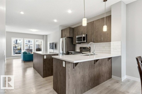 Contemporary kitchen featuring wood-finish cabinetry, white subway tile backsplash, and stainless steel appliances - 17451 77 Street, Edmonton, AB - Indoor Photo Showing Kitchen With Upgraded Kitchen