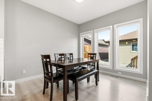 Dining area featuring light wood-finish flooring, light grey painted walls, and three large windows with white trim - 17451 77 Street, Edmonton, AB - Indoor Photo Showing Dining Room