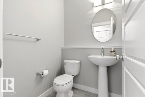 Pedestal sink with chrome faucet, oval mirror, and wall-mounted light fixture - 17451 77 Street, Edmonton, AB - Indoor Photo Showing Bathroom