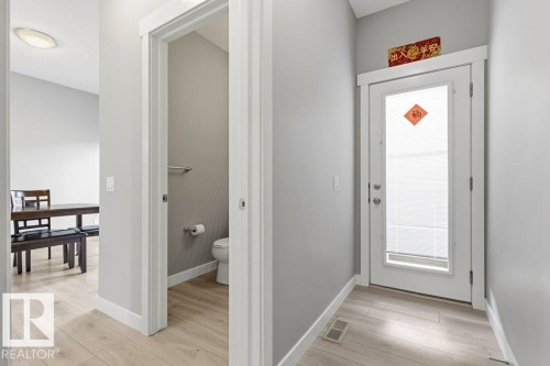 Entryway featuring light wood-finish flooring, a contemporary white entry door with integrated blinds, and a neutral color palette - 17451 77 Street, Edmonton, AB - Indoor Photo Showing Other Room