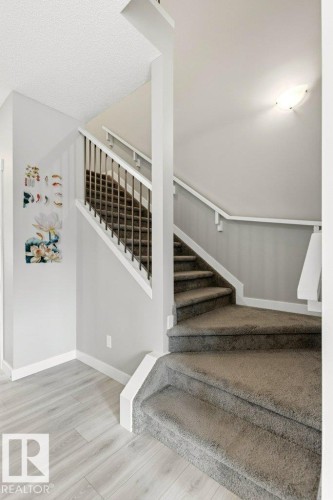 Staircase featuring dark gray carpeting and white risers, complemented by a white handrail and dark metal spindles - 17451 77 Street, Edmonton, AB - Indoor Photo Showing Other Room