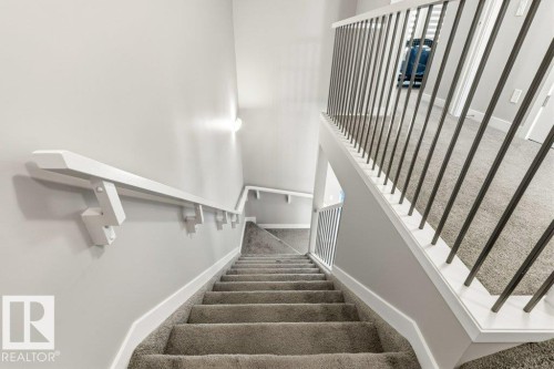 Carpeted staircase with white trim, a white handrail, and a metal spindle railing - 17451 77 Street, Edmonton, AB - Indoor Photo Showing Other Room