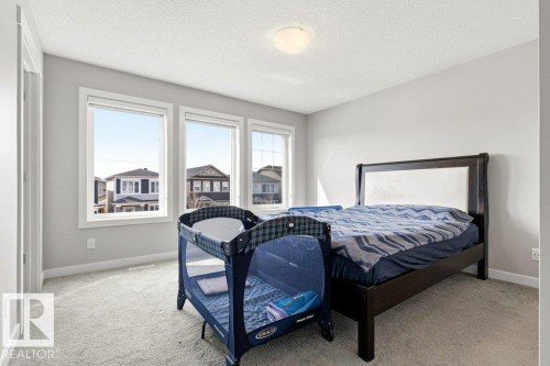 Bright room featuring three large windows, light gray wall paint, textured ceiling, light-toned carpet flooring, and white trim - 17451 77 Street, Edmonton, AB - Indoor Photo Showing Bedroom