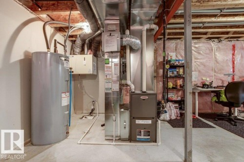 Basement utility area featuring a hot water heater, furnace, exposed ductwork, exposed ceiling joists, and concrete flooring - 17451 77 Street, Edmonton, AB - Indoor Photo Showing Basement