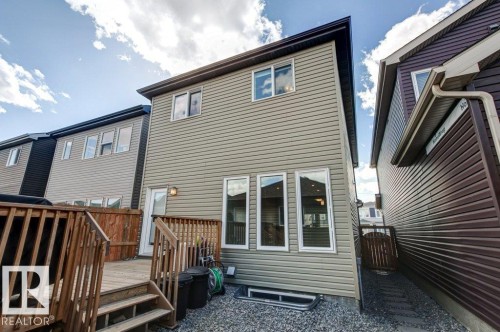Rear exterior featuring light beige horizontal siding, a multi-level wood deck, and a gravel ground cover - 17451 77 Street, Edmonton, AB - Outdoor With Exterior