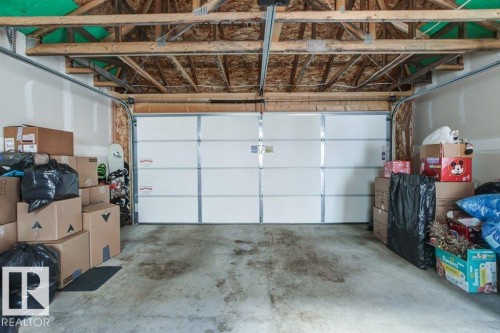Garage featuring a paneled overhead door, exposed wooden ceiling joists, and concrete flooring - 17451 77 Street, Edmonton, AB - Indoor Photo Showing Garage