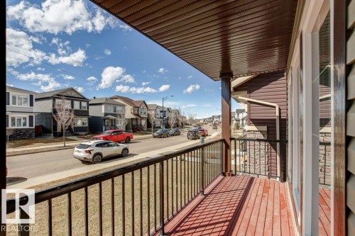 Covered balcony with wood-finish decking, black metal railings, and a solid wood support column - 17451 77 Street, Edmonton, AB - Outdoor