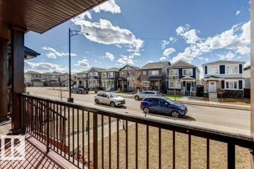 Covered porch with wood-finish ceiling and dark railing overlooking a street with various residential properties - 17451 77 Street, Edmonton, AB - Outdoor