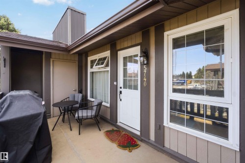 Covered entryway featuring a white paneled door with glass inserts, an exterior sconce, and white-framed windows with grilles - 5740 172 Street, Edmonton, AB - Outdoor With Exterior