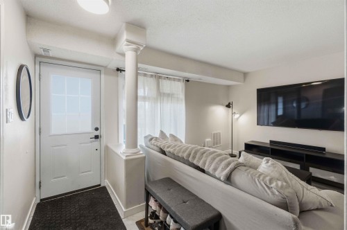 Bright living area featuring a white paneled door with glass inserts, a decorative column, and light-toned walls - 5740 172 Street, Edmonton, AB - Indoor