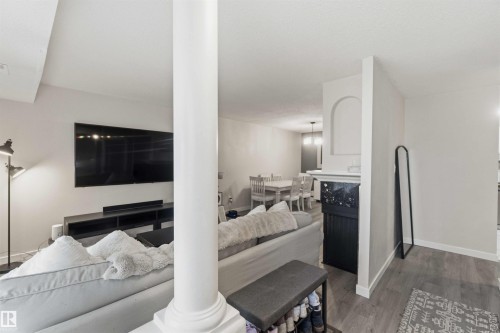 Open-concept living area featuring a prominent white column, wood-finish flooring, and light-toned walls - 5740 172 Street, Edmonton, AB - Indoor