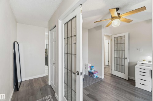 Interior hallway featuring wood-finish flooring, light gray wall paint, and multiple white paneled doors - 5740 172 Street, Edmonton, AB - Indoor Photo Showing Other Room