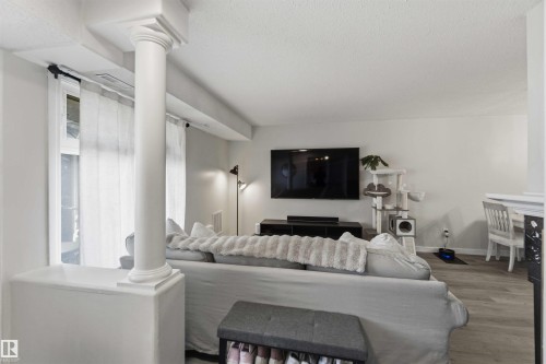 Open concept living area featuring a decorative column, large windows with sheer privacy curtains, light wood-finish flooring, and ample wall space for entertainment - 5740 172 Street, Edmonton, AB - Indoor Photo Showing Living Room