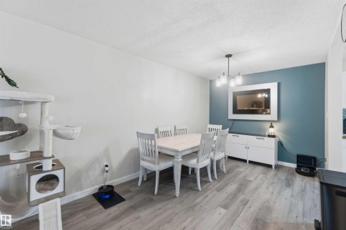 Dining area featuring wood-finish flooring, a contemporary chandelier, and a recessed wall-mounted electric fireplace - 5740 172 Street, Edmonton, AB - Indoor Photo Showing Dining Room