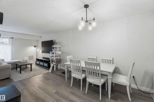 Open-concept living and dining area featuring wood-finish flooring, recessed lighting, and a contemporary chandelier with glass shades - 5740 172 Street, Edmonton, AB - Indoor