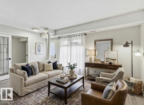 Living area featuring wood-finish flooring, light neutral wall tones, a ceiling-mounted light fixture, and a glass-paneled interior door - 5740 172 Street, Edmonton, AB - Indoor Photo Showing Living Room