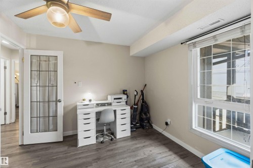 Room featuring wood-finish flooring, a ceiling fan with integrated lighting, and a large window with blinds - 5740 172 Street, Edmonton, AB - Indoor Photo Showing Office
