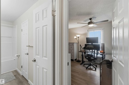 Well-lit room featuring wood-finish flooring, a ceiling fan with integrated lighting, and a window with blinds - 5740 172 Street, Edmonton, AB - Indoor Photo Showing Office