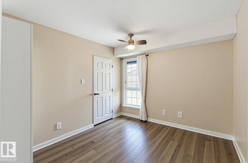 Room featuring wood-finish flooring, neutral wall tones, a paneled door, and a multi-pane window - 5740 172 Street, Edmonton, AB - Indoor Photo Showing Other Room