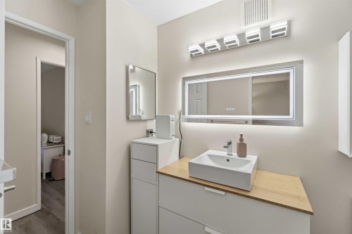 Bathroom vanity featuring a vessel sink, light wood-finish countertop, and integrated storage - 5740 172 Street, Edmonton, AB - Indoor