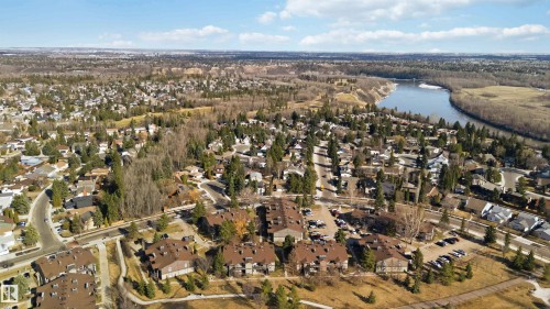 Expansive aerial perspective showcasing a residential area with varied housing styles, mature trees, and a prominent river winding through a natural landscape - 5740 172 Street, Edmonton, AB - Outdoor With View