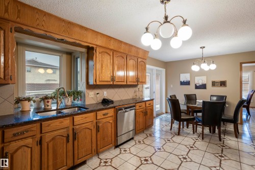 Kitchen featuring wood cabinetry, dark countertops, and a stainless steel dishwasher - 9831 158 Avenue, Edmonton, AB - Indoor