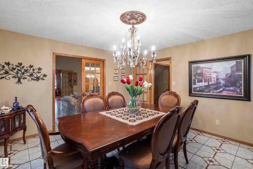 Dining area featuring a decorative chandelier with crystal accents, light beige wall paint, and patterned tile flooring - 9831 158 Avenue, Edmonton, AB - Indoor Photo Showing Dining Room