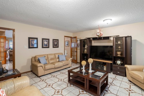 Living area featuring patterned tile flooring, warm neutral wall tones, and a ceiling-mounted light fixture - 9831 158 Avenue, Edmonton, AB - Indoor Photo Showing Living Room