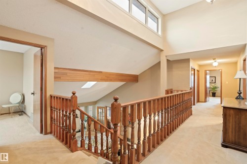 Upper-level landing featuring wood-finish railings, high ceilings, and a skylight - 9831 158 Avenue, Edmonton, AB - Indoor Photo Showing Other Room