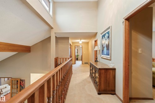 Upper-level hallway featuring a light-toned carpet, natural wood banister, and a high ceiling with clerestory windows - 9831 158 Avenue, Edmonton, AB - Indoor Photo Showing Other Room