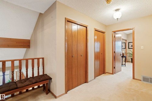 Carpeted hallway featuring multiple wood-finish doors, wood trim, and a decorative ceiling light fixture - 9831 158 Avenue, Edmonton, AB - Indoor Photo Showing Other Room