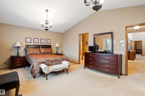 Spacious bedroom featuring vaulted ceilings, plush carpeting, warm neutral wall tones, and a chandelier lighting fixture - 9831 158 Avenue, Edmonton, AB - Indoor Photo Showing Bedroom
