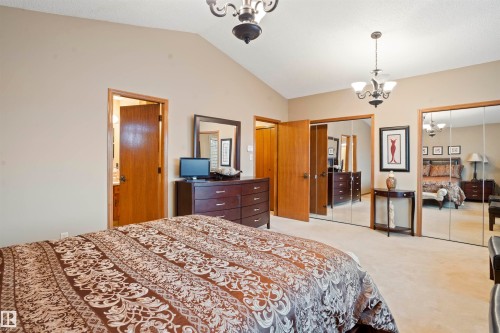 Vaulted ceiling bedroom featuring plush carpeting, two sets of mirrored closet doors, and wood-finish interior doors - 9831 158 Avenue, Edmonton, AB - Indoor Photo Showing Bedroom