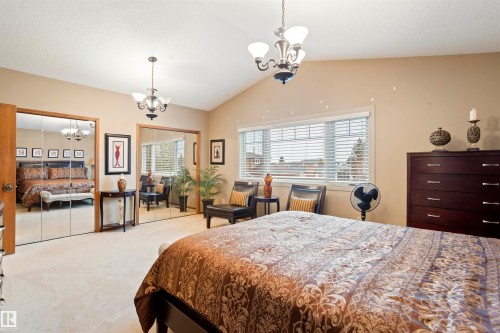 Carpeted bedroom featuring vaulted ceilings, a window with horizontal blinds, and a multi-light chandelier - 9831 158 Avenue, Edmonton, AB - Indoor Photo Showing Bedroom