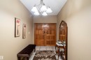 Solid wood double entry doors with decorative panels, overhead chandelier, and light-toned tile flooring - 9831 158 Avenue, Edmonton, AB  - Indoor Photo Showing Other Room 