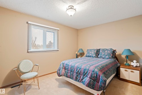 Neutral tone walls with a textured ceiling and a single window featuring horizontal blinds - 9831 158 Avenue, Edmonton, AB - Indoor Photo Showing Bedroom